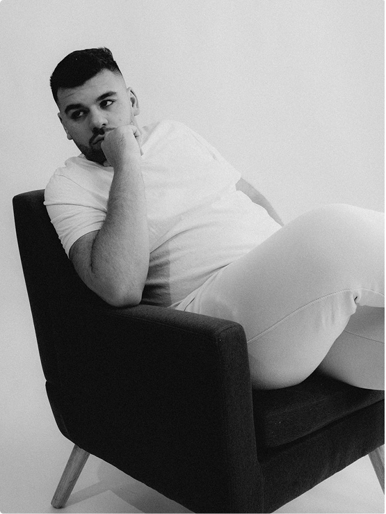 Photo de Cyril bigayon. Photo en noir et blanc. Il est assis sur un fauteuil et regarde derrière l'objectif.